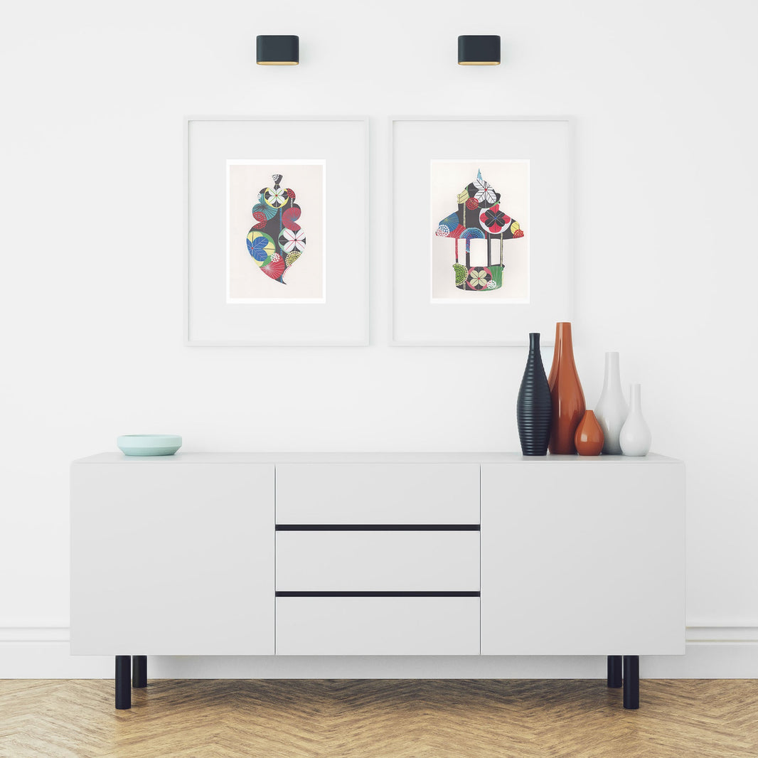 Two framed fine art prints, by Lis Gonçalves. Open edition, signed by the artist (printed in Hahnemühle matt fibre paper) featuring a Lisbon Kiosk and a Portuguese Heart in a modern living room with a white sideboard, decorative vases, and framed artwork on a white wall.