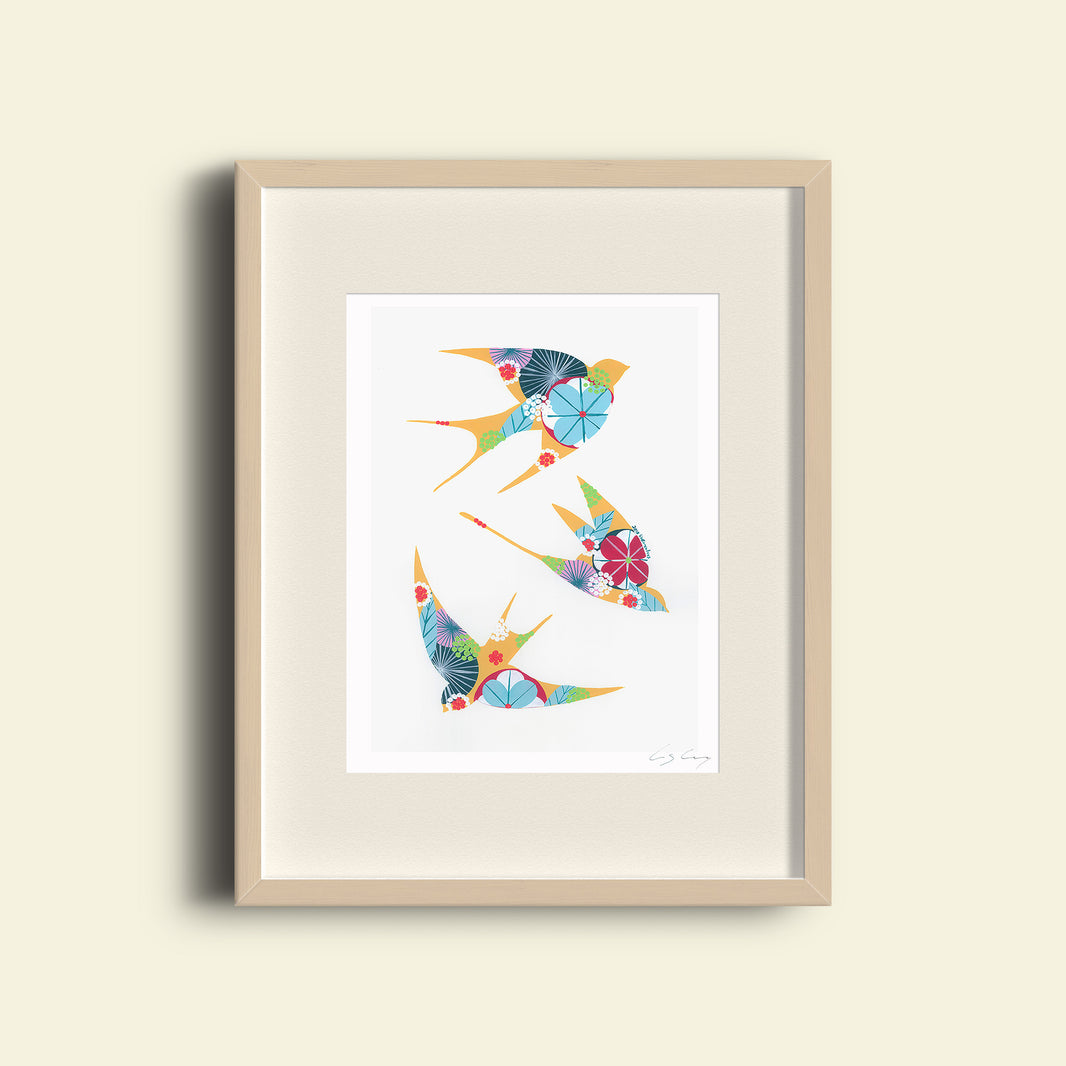 A framed fine art print, by Lis Gonçalves. Open edition, signed by the artist (printed in Hahnemühle matt fibre paper) featuring colorful swallows on a white background