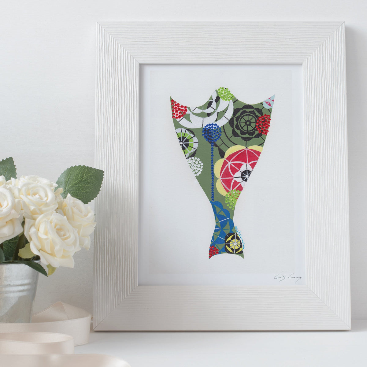 A framed fine art print, by Lis Gonçalves. Open edition, signed by the artist (printed in Hahnemühle matt fibre paper) featuring a a colorful cod fish illustration on a white surface with flowers.