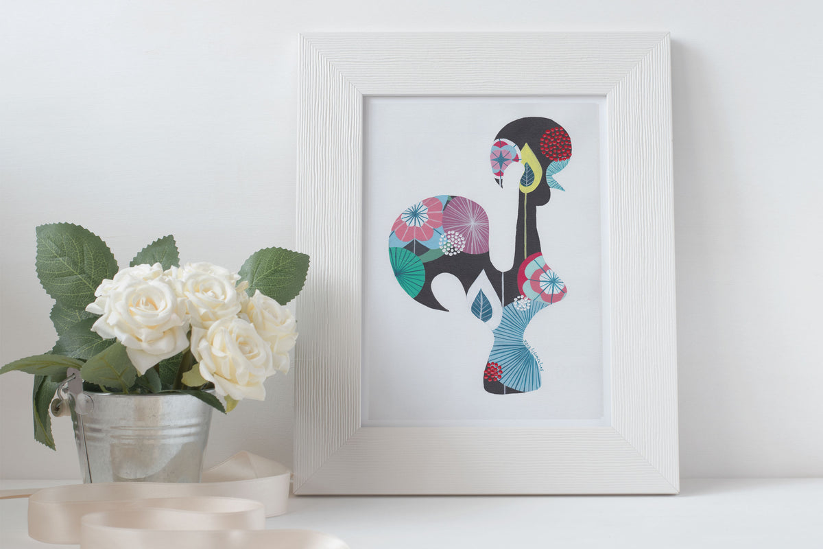 A framed fine art print, by Lis Gonçalves. Open edition, signed by the artist (printed in Hahnemühle matt fibre paper) featuring a colorful Portuguese rooster on a white surface with flowers and candles.
