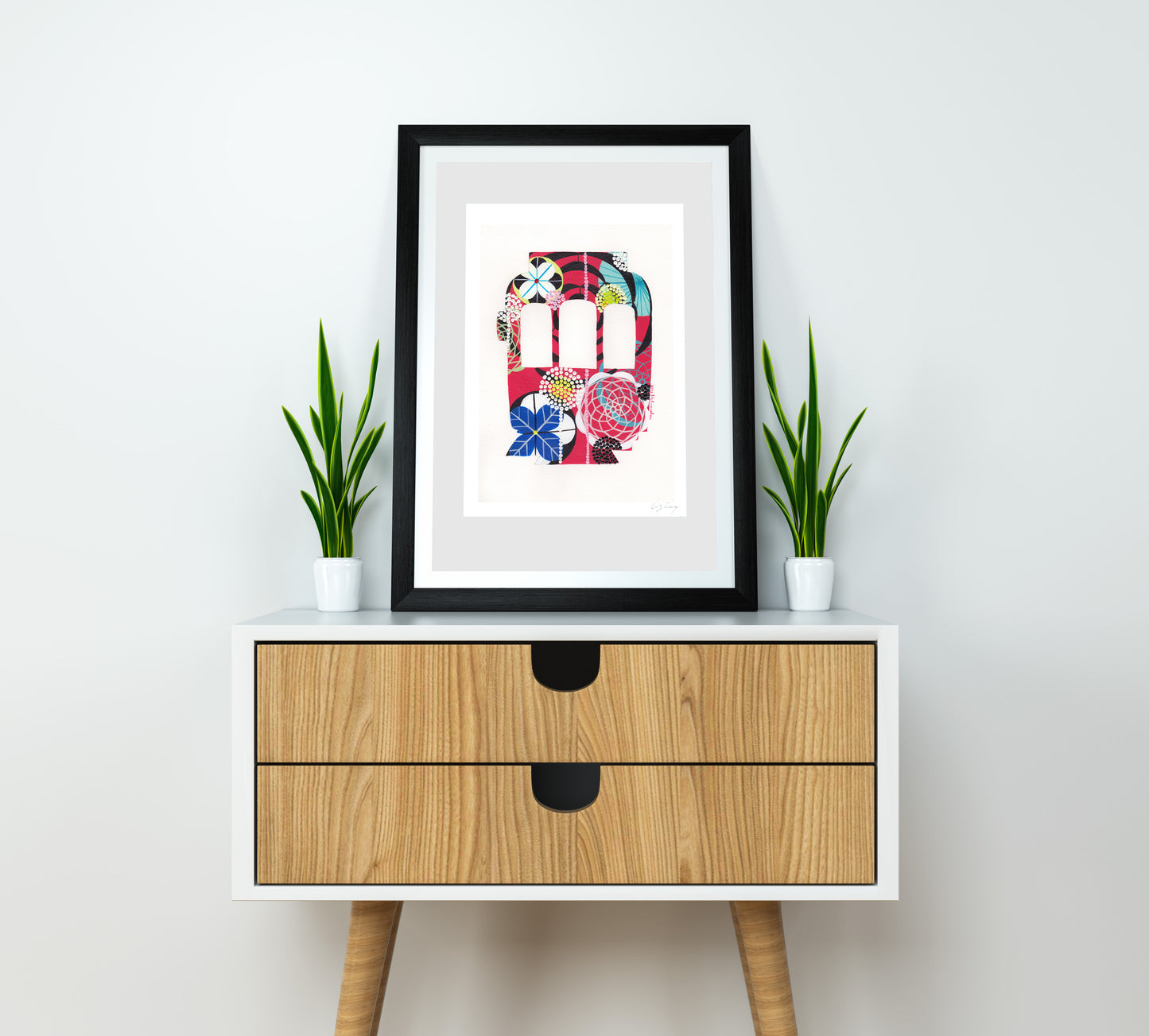 A framed fine art print, by Lis Gonçalves. Open edition, signed by the artist (printed in Hahnemühle matt fibre paper) featuring a colorful Lisbon tram on a wooden side table with two potted plants.