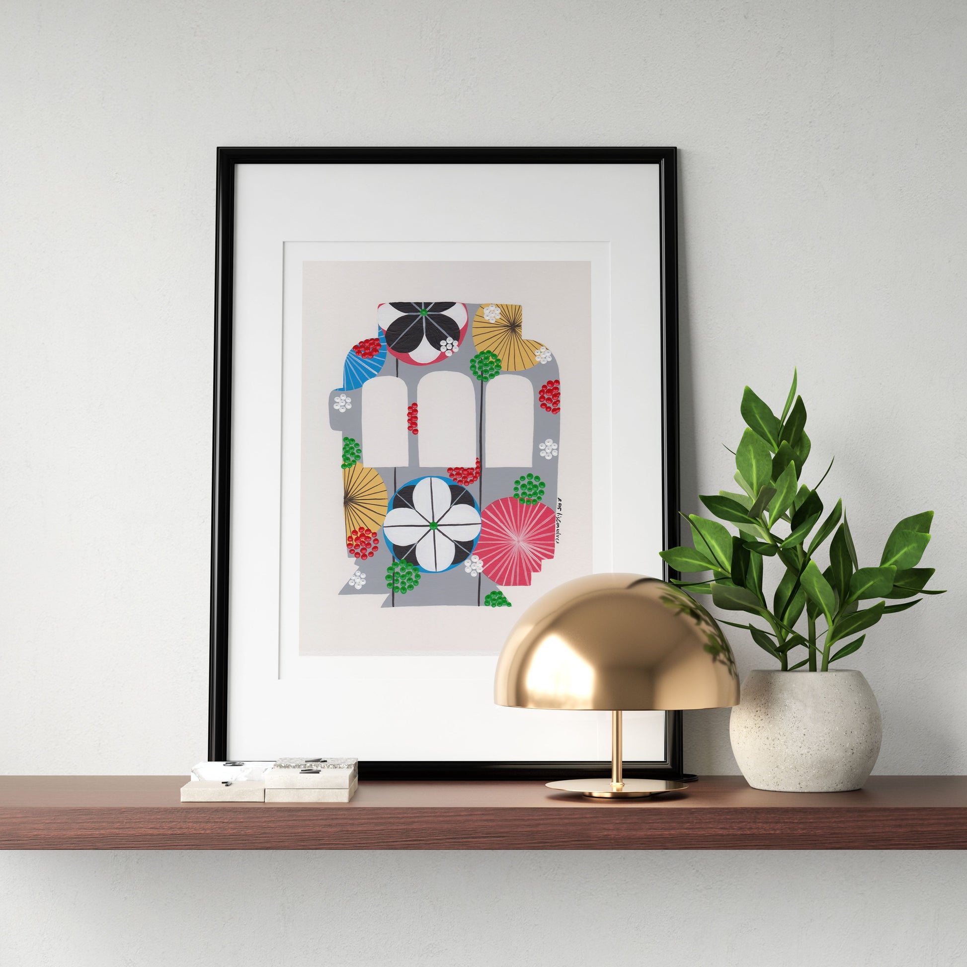 A framed fine art print, by Lis Gonçalves. Open edition, signed by the artist (printed in Hahnemühle matt fibre paper) featuring a colorful Lisbon tram on a wooden shelf with a gold lamp and plant against a white wall.