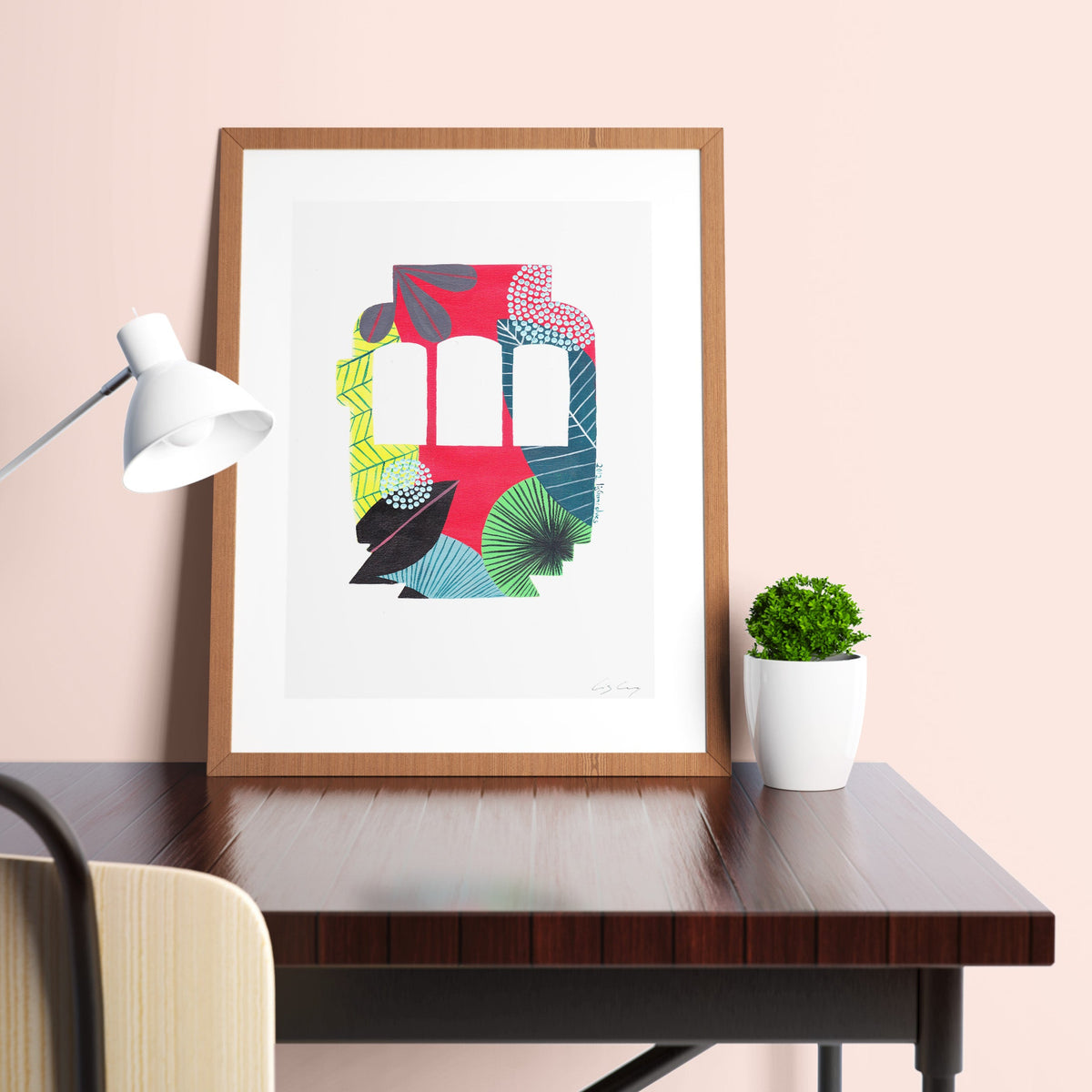 A framed fine art print, by Lis Gonçalves. Open edition, signed by the artist (printed in Hahnemühle matt fibre paper) featuring a colorful Lisbon tram displayed on a desk with a lamp and plant.