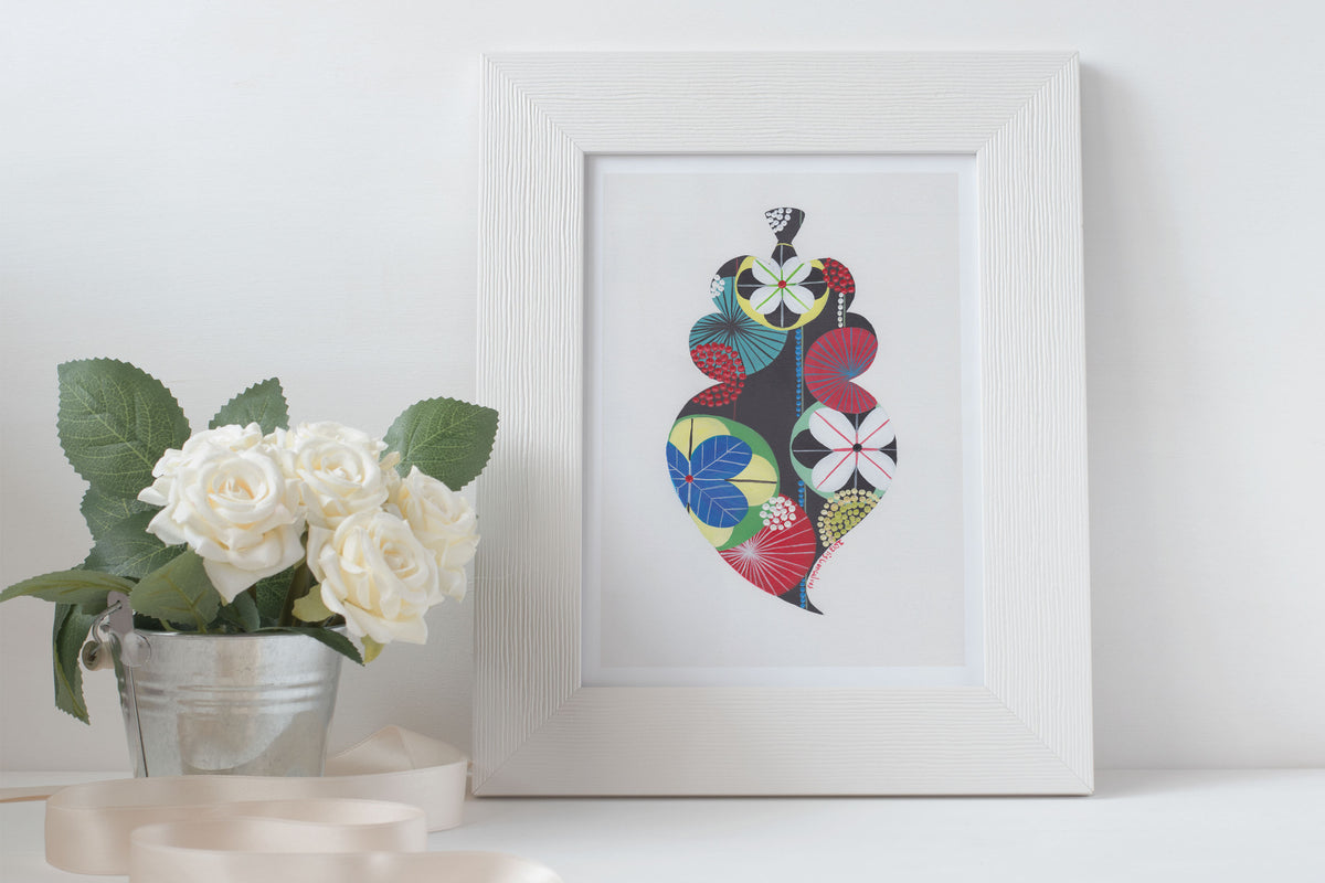 A framed fine art print, by Lis Gonçalves. Open edition, signed by the artist (printed in Hahnemühle matt fibre paper) featuring a colorful Portuguese Viana heart on a white surface with flowers and candles.