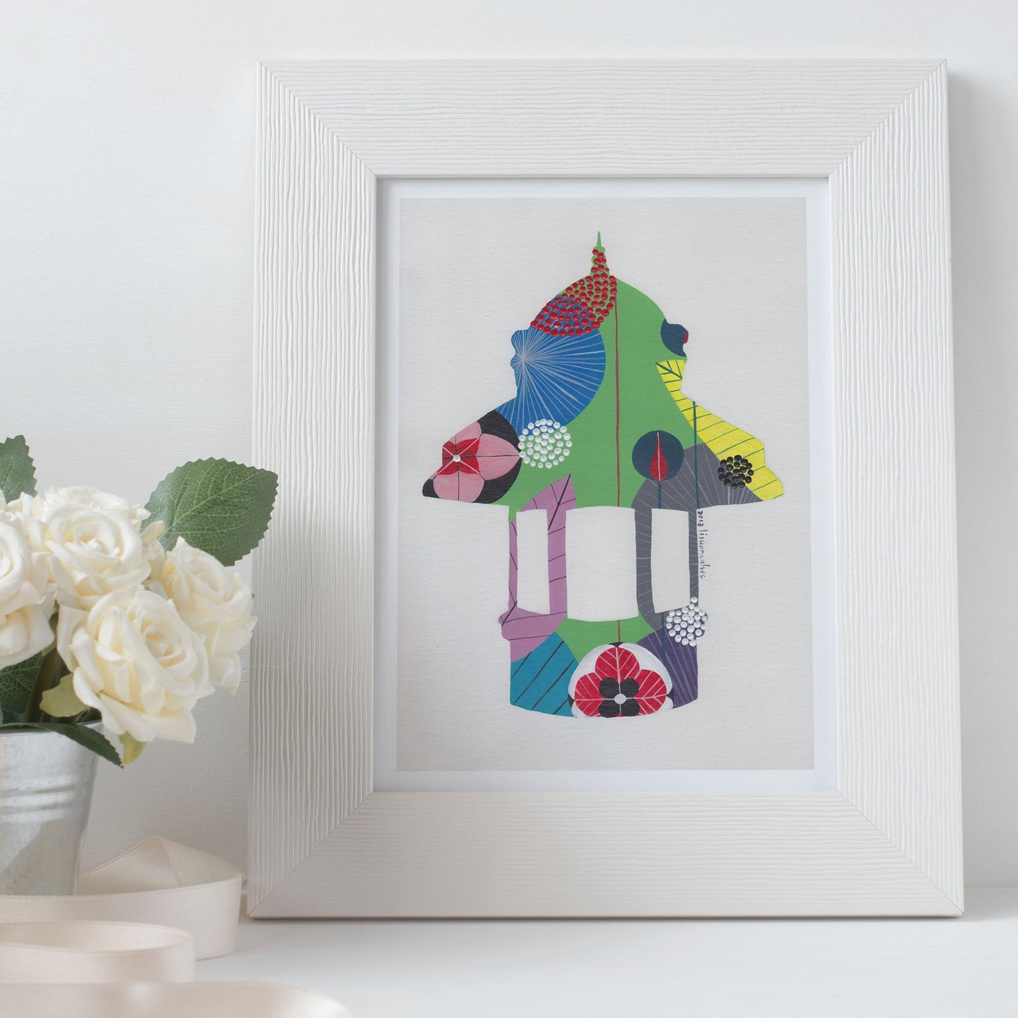 A framed fine art print, by Lis Gonçalves. Open edition, signed by the artist (printed in Hahnemühle matt fibre paper) featuring a colorful abstract Lisbon kiosk on a white surface with a potted plant.