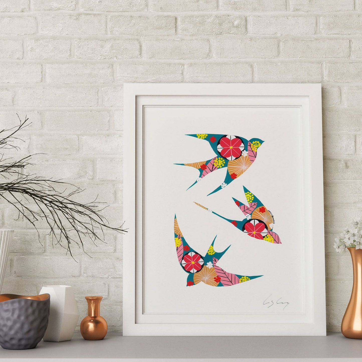 A framed fine art print, by Lis Gonçalves. Open edition, signed by the artist (printed in Hahnemühle matt fibre paper) featuring colorful swallows on a white wall with decorative vases and plants.