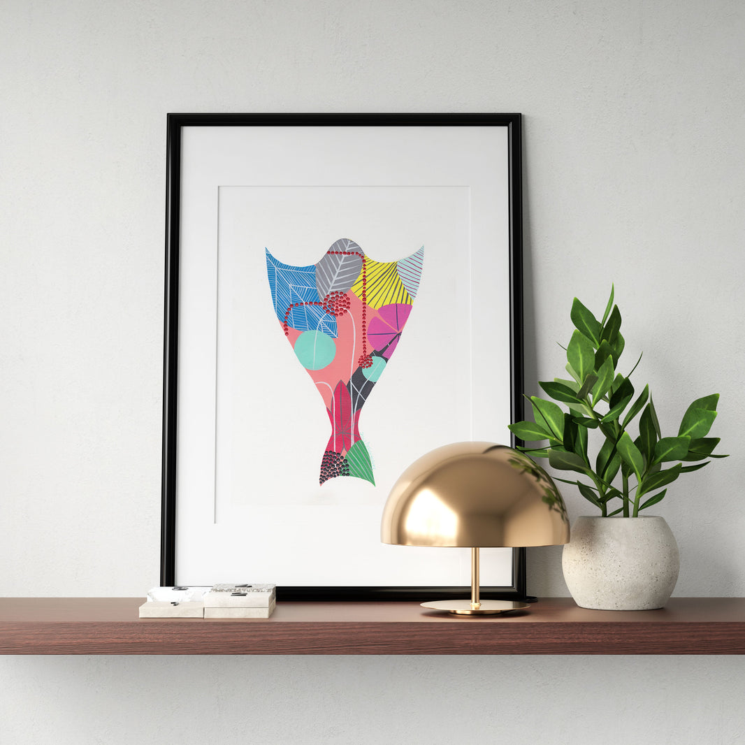 A framed fine art print, by Lis Gonçalves. Open edition, signed by the artist (printed in Hahnemühle matt fibre paper) featuring a colorful cod design on a wooden shelf with a gold lamp and plant.