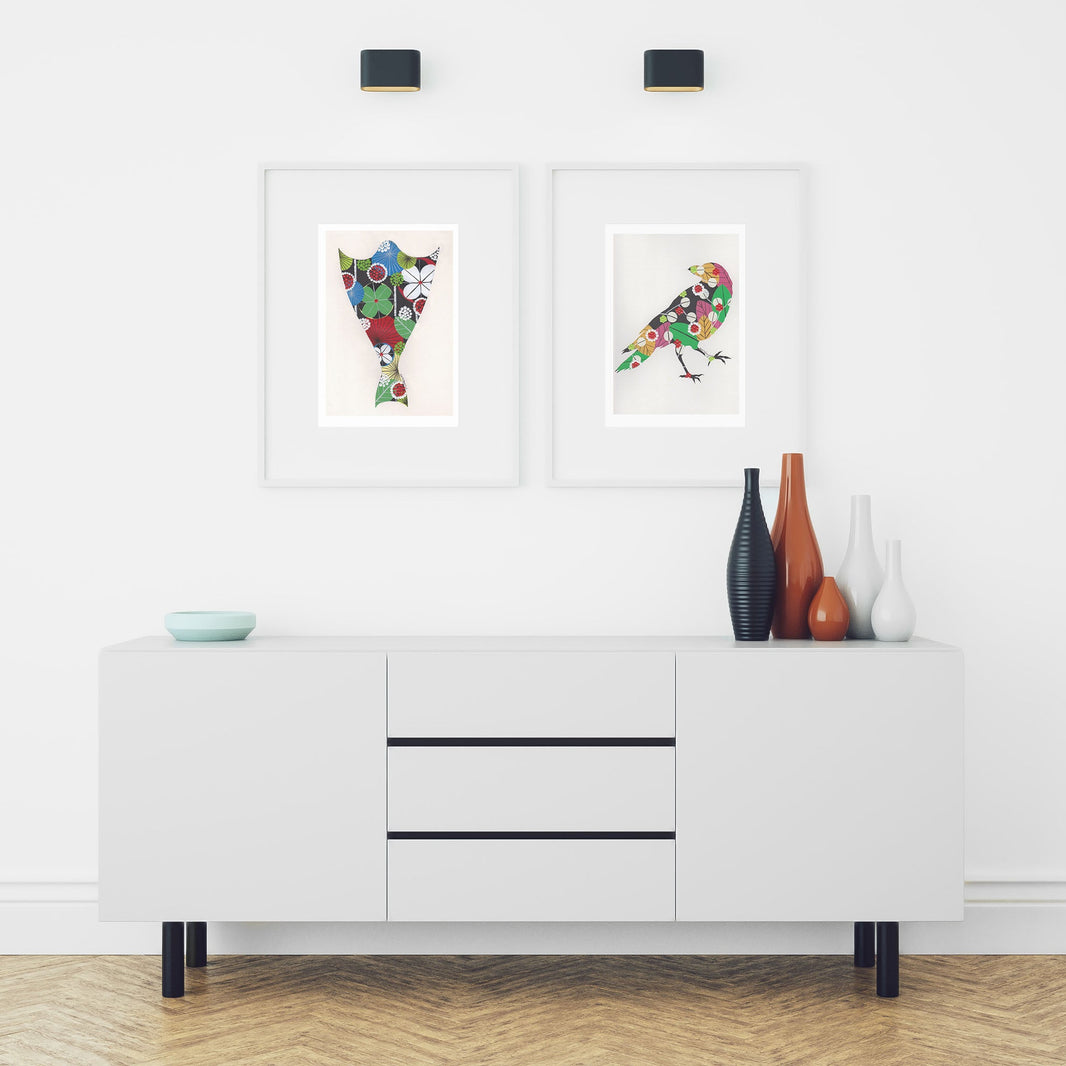 Two framed fine art prints, by Lis Gonçalves. Open edition, signed by the artist (printed in Hahnemühle matt fibre paper) featuring a raven and a bacalhau in a modern interior with a white cabinet and decorative vases.