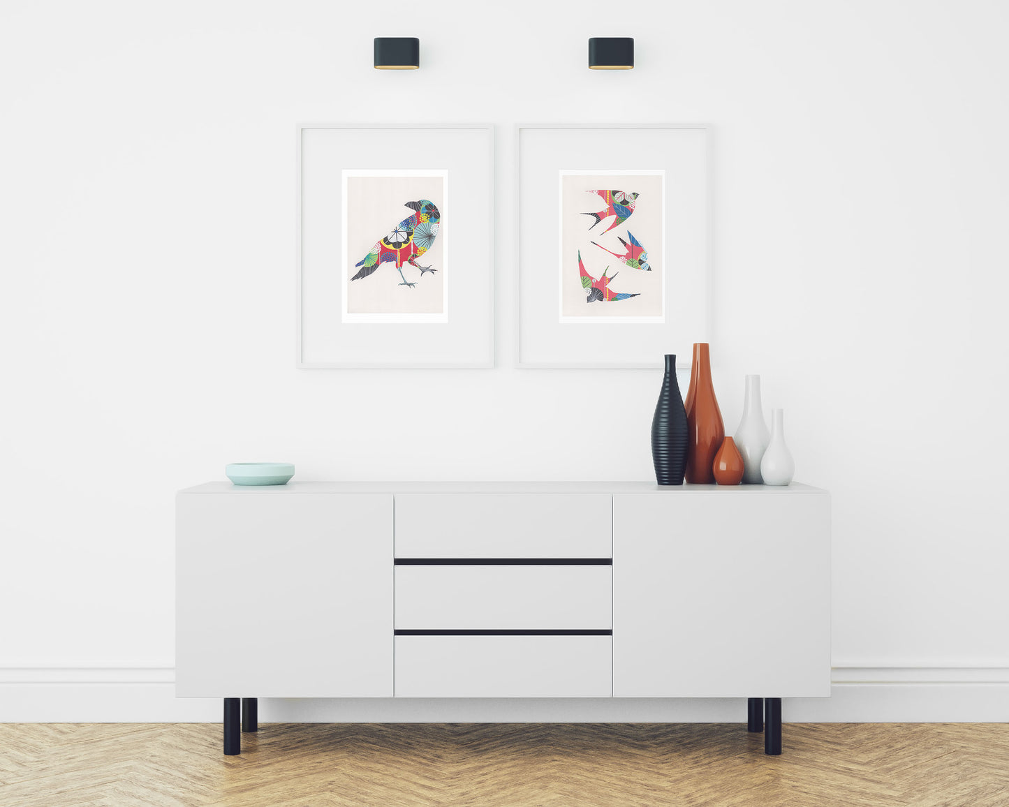 Two framed fine art prints, by Lis Gonçalves. Open edition, signed by the artist (printed in Hahnemühle matt fibre paper) featuring colorful swallows and a raven in a modern interior with a white sideboard and decorative vases on a white wall.