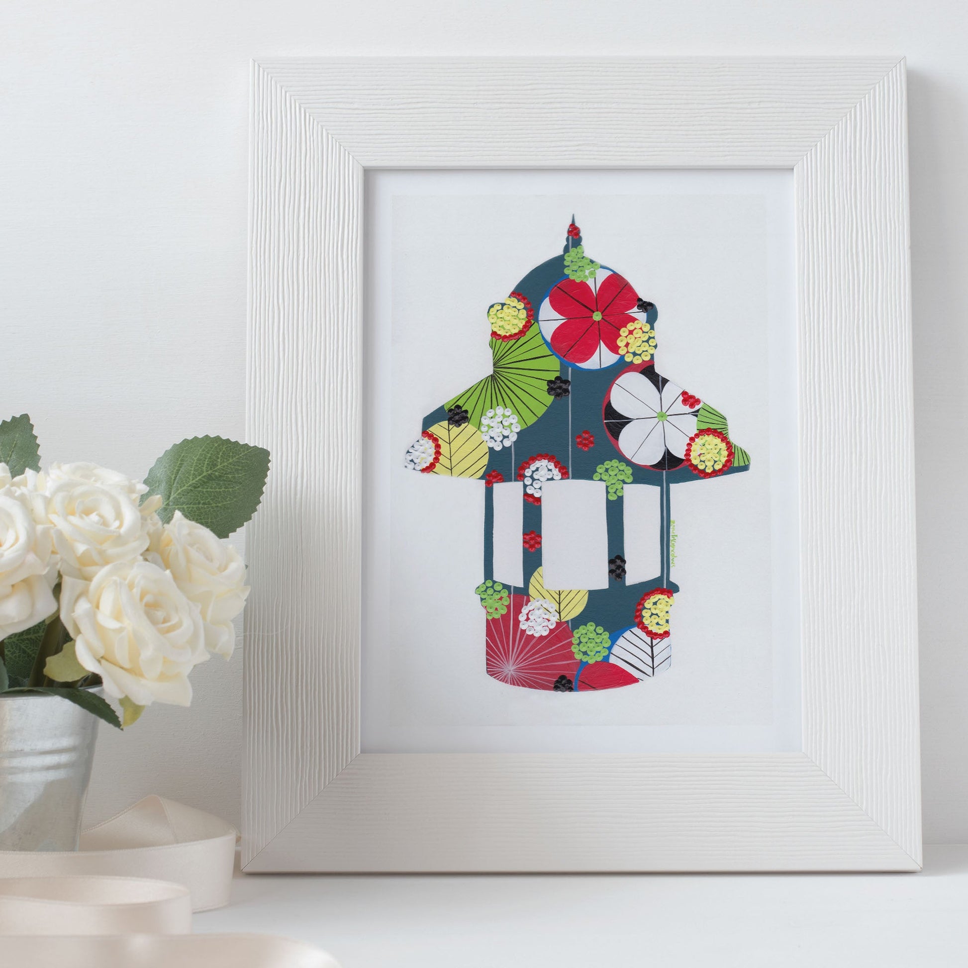 A framed fine art print, by Lis Gonçalves. Open edition, signed by the artist (printed in Hahnemühle matt fibre paper) featuring a colorful Lisbon Kiosk in a white frame and white surface.
