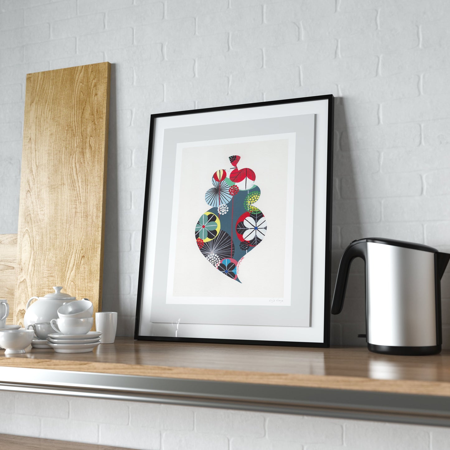A framed fine art print, by Lis Gonçalves. Open edition, signed by the artist (printed in Hahnemühle matt fibre paper) featuring a colorful Portuguese Viana heart, leaning on a wooden kitchen counter next to a kettle and a wooden board.
