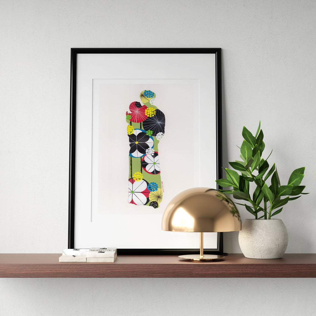 A framed fine art print, by Lis Gonçalves. Open edition, signed by the artist (printed in Hahnemühle matt fibre paper) featuring a colorful Saint Anthony on a wooden shelf with a gold lamp and plant against a white wall.