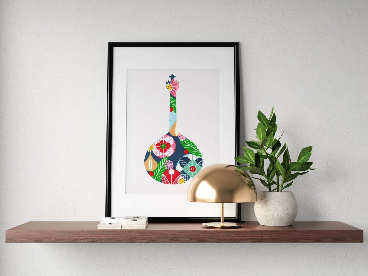 A framed fine art print, by Lis Gonçalves. Open edition, signed by the artist (printed in Hahnemühle matt fibre paper) featuring a colorful Portuguese guitar, on a wooden shelf with a lamp and plant.