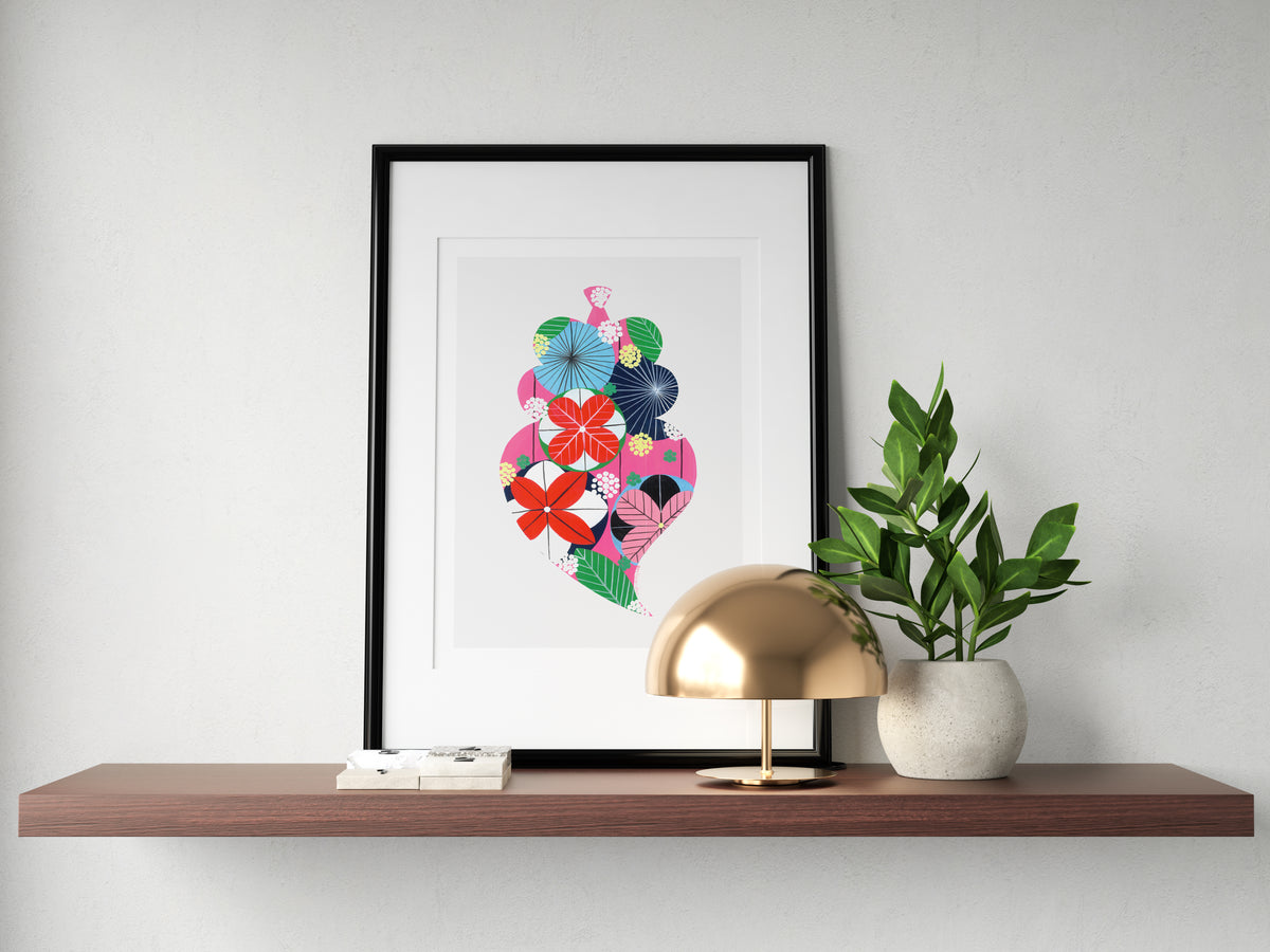A framed fine art print, by Lis Gonçalves. Open edition, signed by the artist (printed in Hahnemühle matt fibre paper) featuring a colorful Portuguese Viana heart on a wooden shelf with a gold lamp and plant.