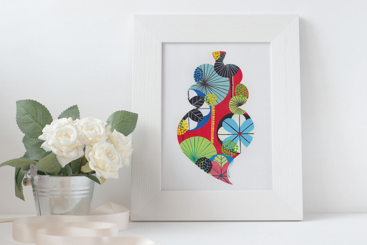 A framed fine art print, by Lis Gonçalves. Open edition, signed by the artist (printed in Hahnemühle matt fibre paper) featuring a colorful Portuguese Viana heart on a white surface with flowers.